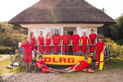 Gruppenfoto von Rettungsschwimmern vor einem DLRG-Haus