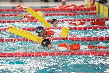 Rettungssportlerin im Hallenbad zieht Puppe und hat Gurtretter in der Hand