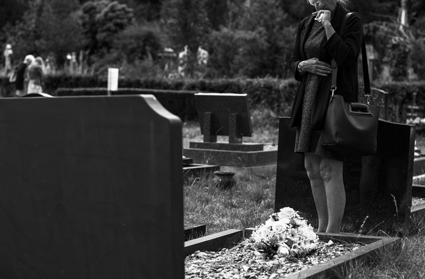 Eine Frau steht am Grab eines Angehörigen