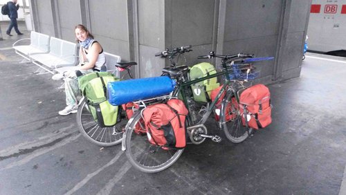 Rettungsschwimmerin mit bepackten Fahrrädern am Bahnsteig.